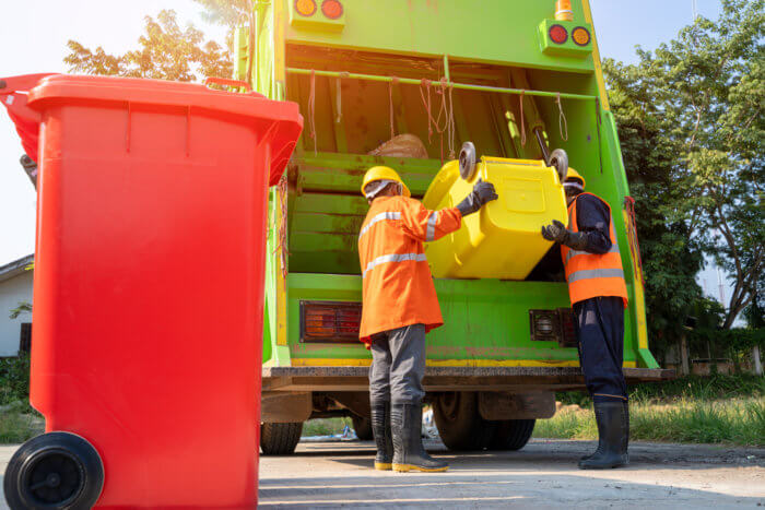 Two,Garbage,Men,Working,Together,On,Emptying,Dustbins,For,Trash