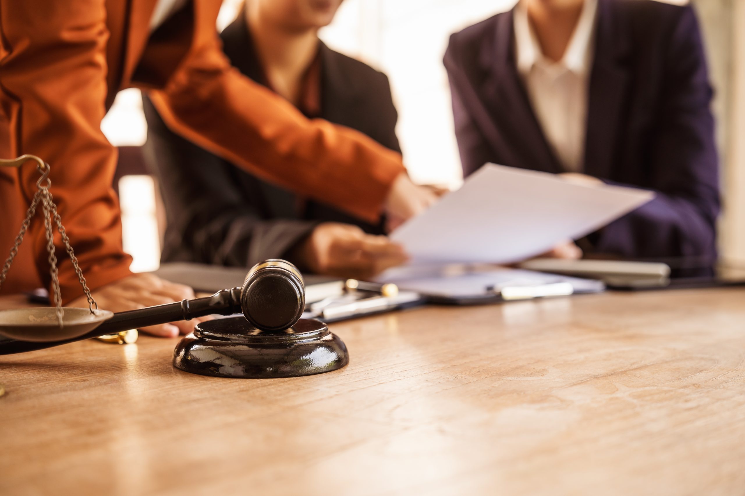 lawyers gathered around table reviewing paperwork with gavel