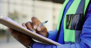 man in yellow vest holding a pen and clipboard