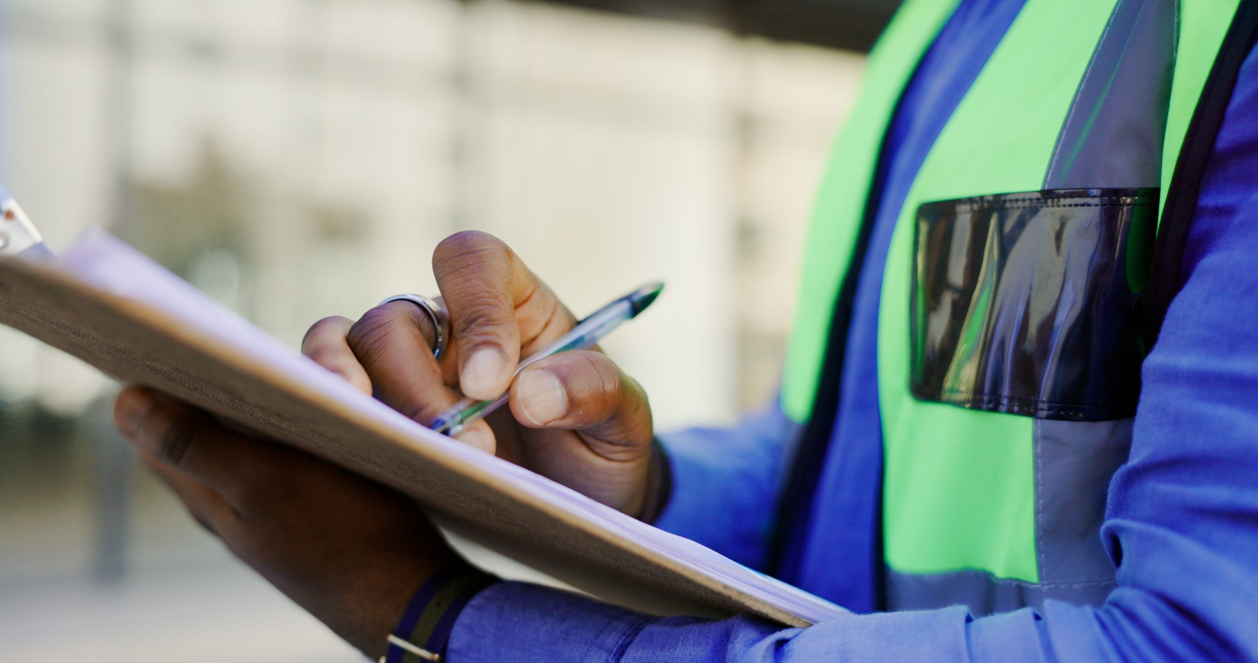 man in yellow vest holding a pen and clipboard