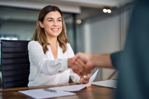 women in button up shaking another person's hand