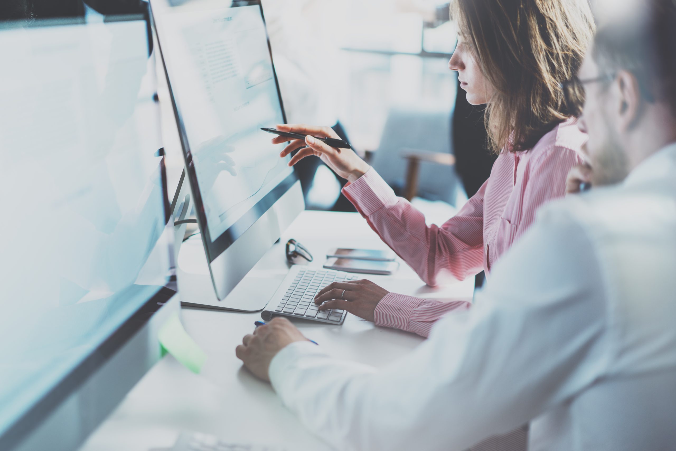 Business woman and business man searching for non-compliant third-parties on their mac desktop computers